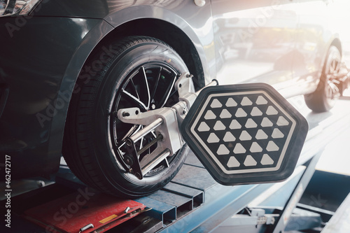 Foto Car wheel balancer calibrate with laser reflector attach on each tire to center driving adjust