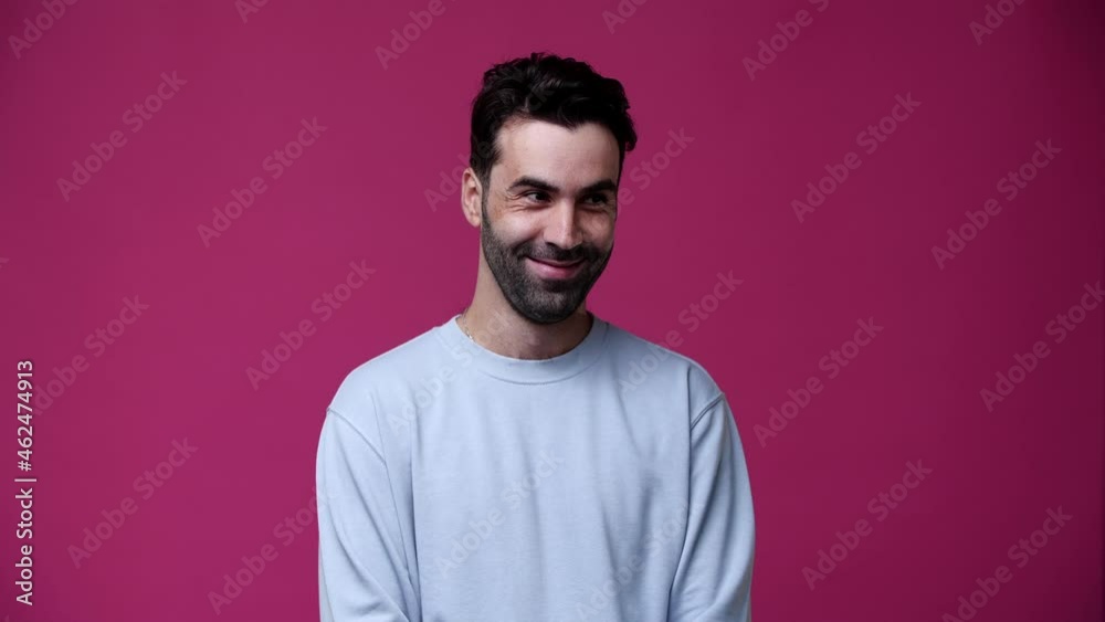 the guy looks around and shows quietly, the background is pink and the guy is dressed in gray