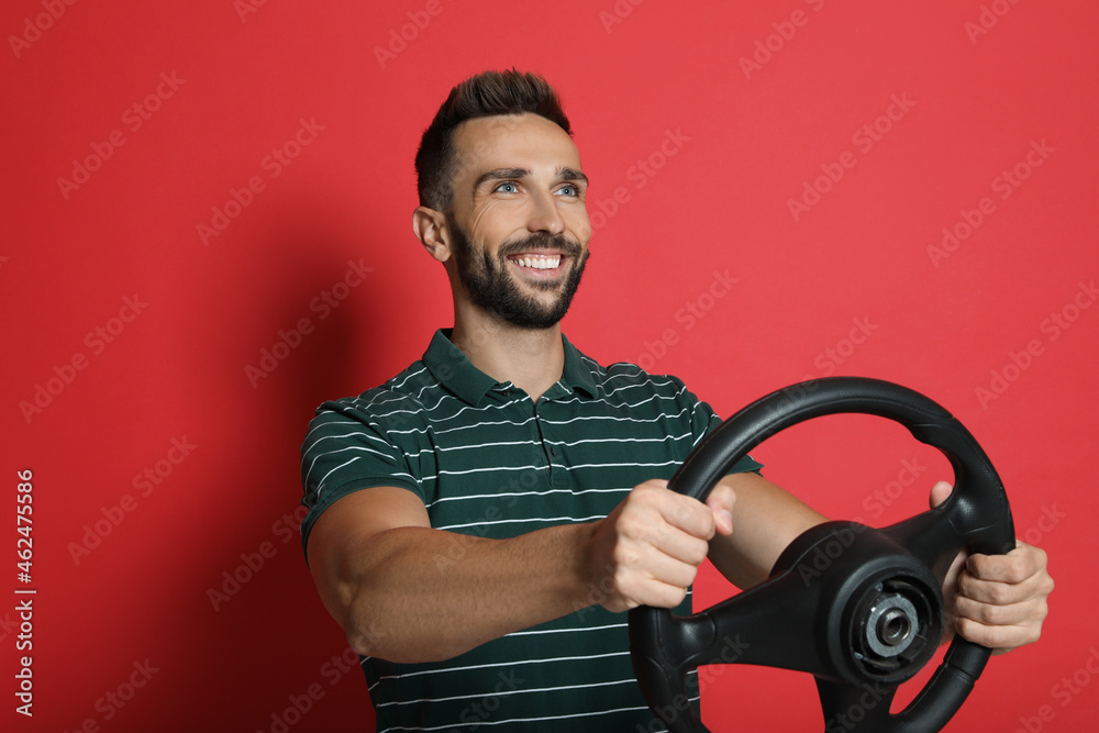 Happy man with steering wheel on red background Happy man with steering wheel on red background