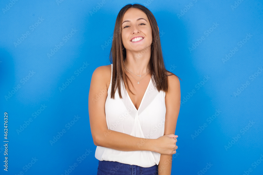 Young european brunette woman wearing white T-shirt on blue background laughing. Young european brunette woman wearing white T-shirt on blue background laughing.
