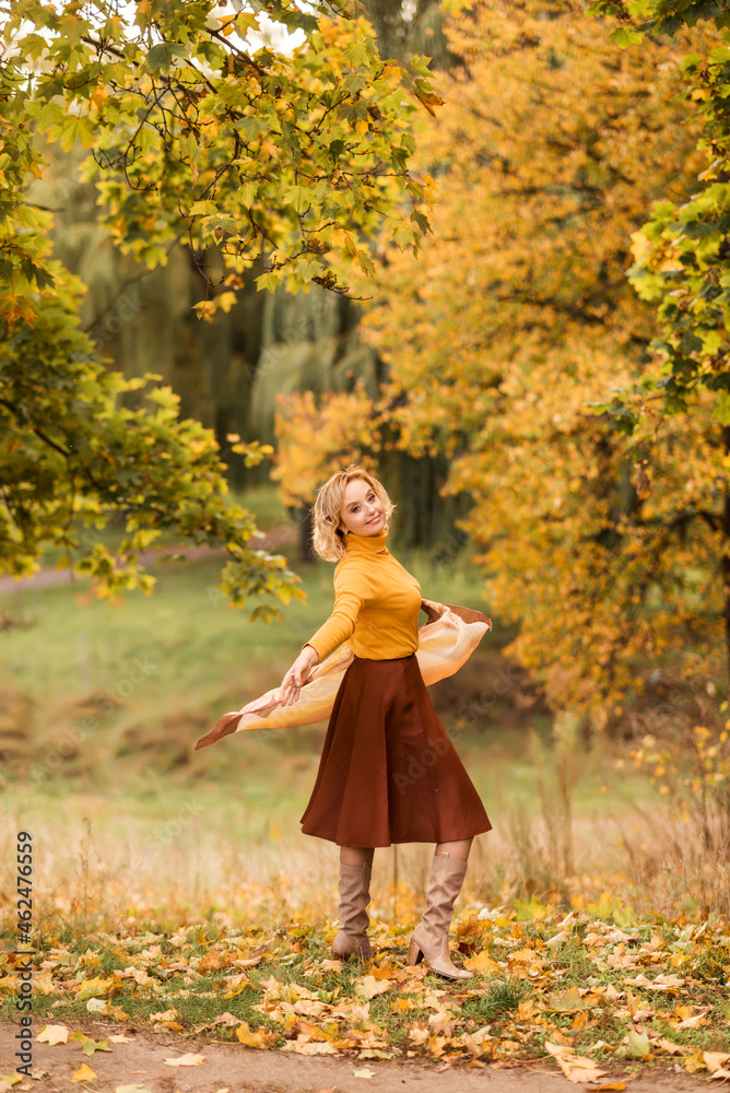 An elderly woman is spinning in an autumn park against a background of yellow leaves. Enjoying life An elderly woman is spinning in an autumn park against a background of yellow leaves. Enjoying life