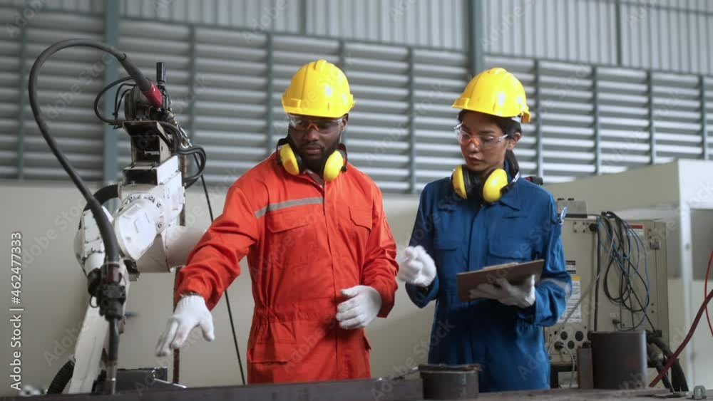 specialist engineer co-worker male and female standing discuss consult robot arm welding machinery input programing data to control and operation in modern manufacture factoy production line . specialist engineer co-worker male and female standing discuss consult robot arm welding machinery input programing data to control and operation in modern manufacture factoy production line .
