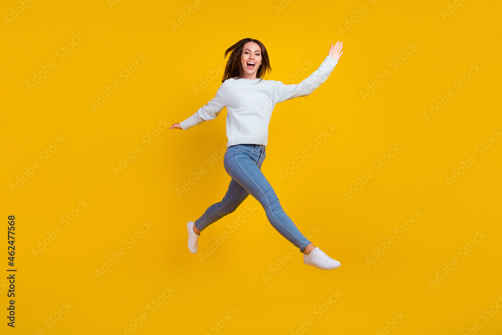 Full length photo of happy young woman jump up walk enjoy good mood isolated on yellow color background