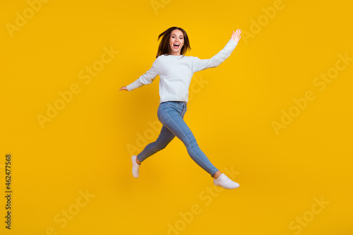 Full length photo of happy young woman jump up walk enjoy good mood isolated on yellow color background © deagreez