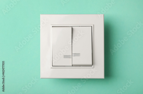 Modern plastic light switch on turquoise background photo