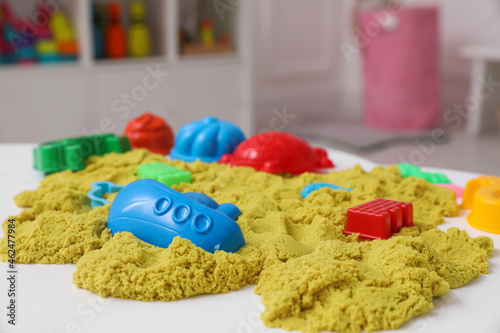 Bright kinetic sand and toys on white table indoors