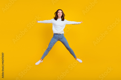 Full body photo of cheerful happy young woman jump up good mood active sale isolated on yellow color background