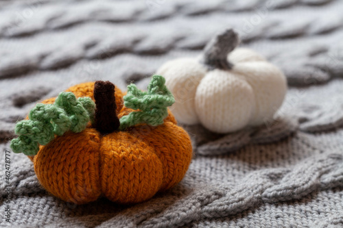 Knitted pumpkin on knitted cover, cozy home background, close-up 
