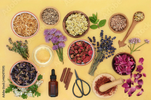 Essential oil aromatherapy preparation with herbs and flowers used in herbal medicine in a mortar. Natural health care concept. Top view, flat lay on mottled yellow background.