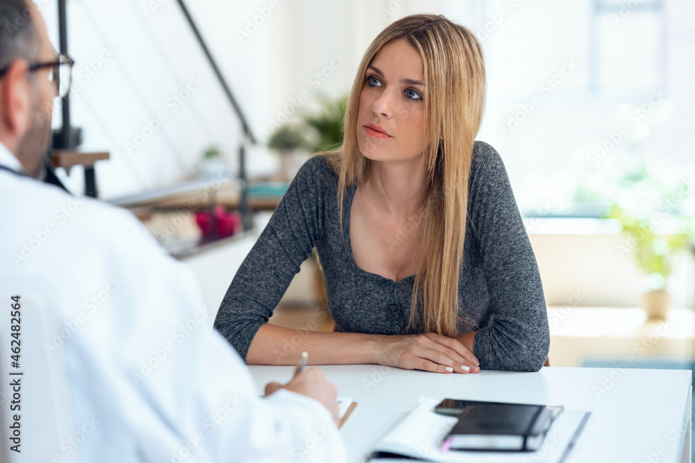 Beautiful patient explaing to her mature male doctor about her pain in the consultation. Beautiful patient explaing to her mature male doctor about her pain in the consultation.