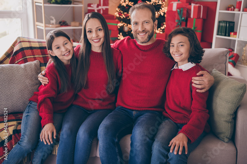 Photo of cheerful family sit sofa cuddle enjoy noel party daddy mommy kid spirit advent marriage wife husband indoors