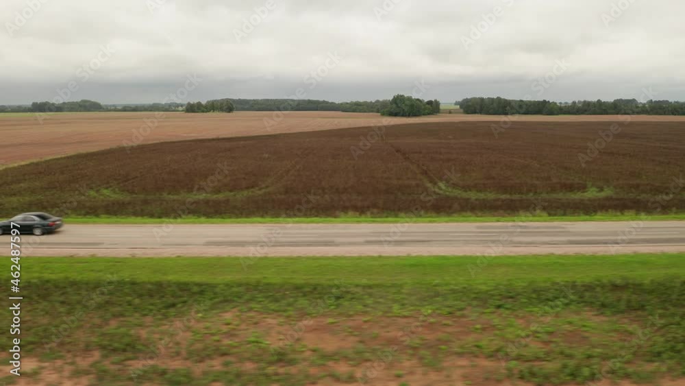 Aerial side view of black sedan car moving in a rural area in autumn. Aerial side view of black sedan car moving in a rural area in autumn.