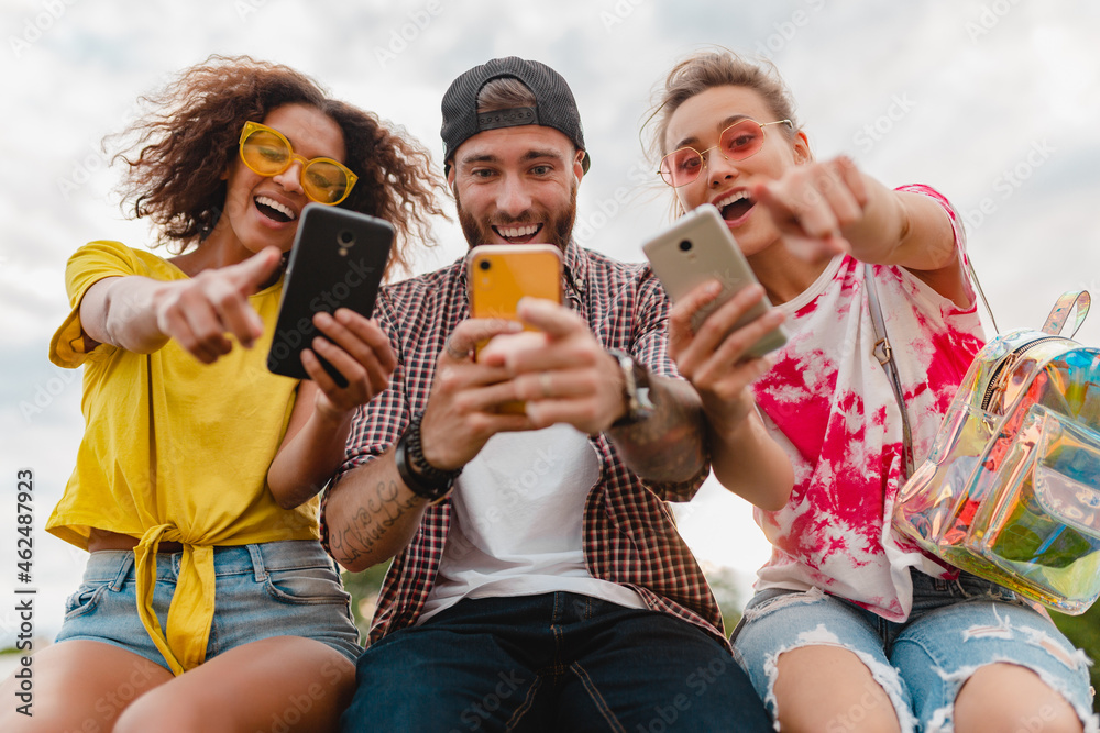 happy young company of smiling friends sitting in park happy young company of smiling friends sitting in park