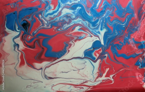 Abstract background of blue-red-white marble. Acrylic paint mixes freely and creates an interesting pattern. Bright saturated shades. Background for the cover of a laptop, laptop. © Olirina