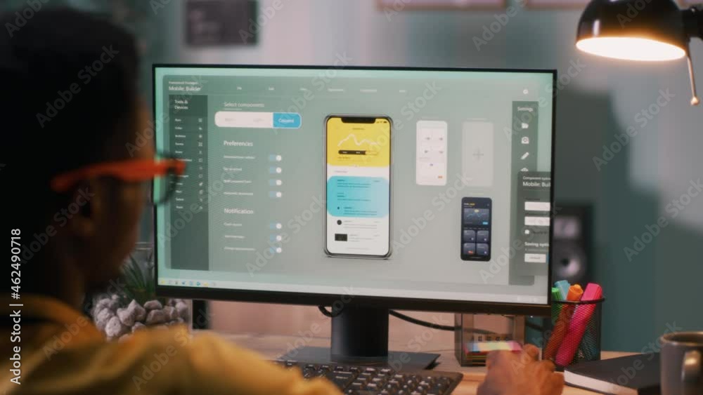 Black male creating cellphone app on computer