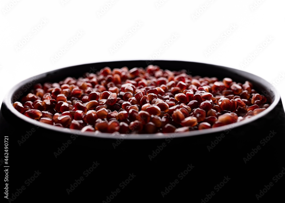 A lot of beautiful red pomegranate seeds in a black bowl