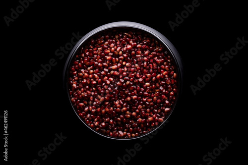 A lot of beautiful red pomegranate seeds in a black bowl