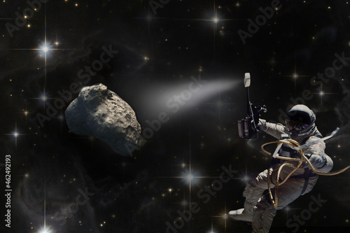 Mission to save the Earth from asteroid fall. Astronaut in space illuminates meteorite. Concept of the victory of mankind over the cosmic threat. Collage. Elements of this image furnished by NASA.