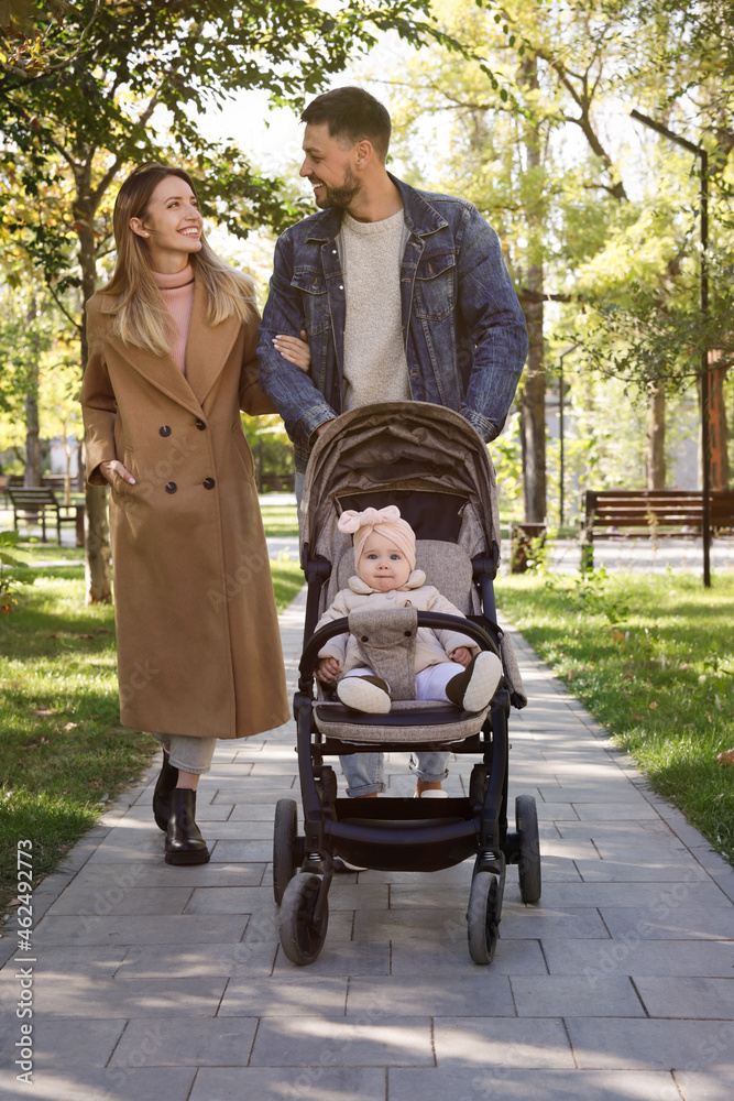 Happy parents walking with their baby in stroller at park on sunny day Happy parents walking with their baby in stroller at park on sunny day