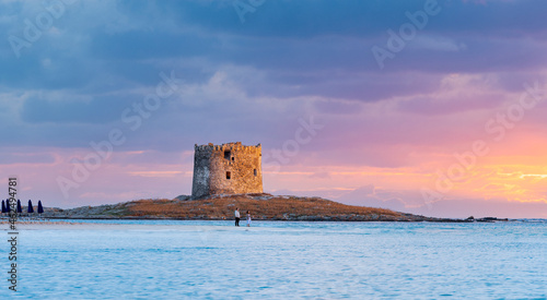 Wallpaper Mural Stunning sunrise over the Aragonese Tower with a couple of tourists enjoying the landscape from La Pelosa Beach, a white sand beach located in Stintino, north-west Sardinia, Italy. Torontodigital.ca