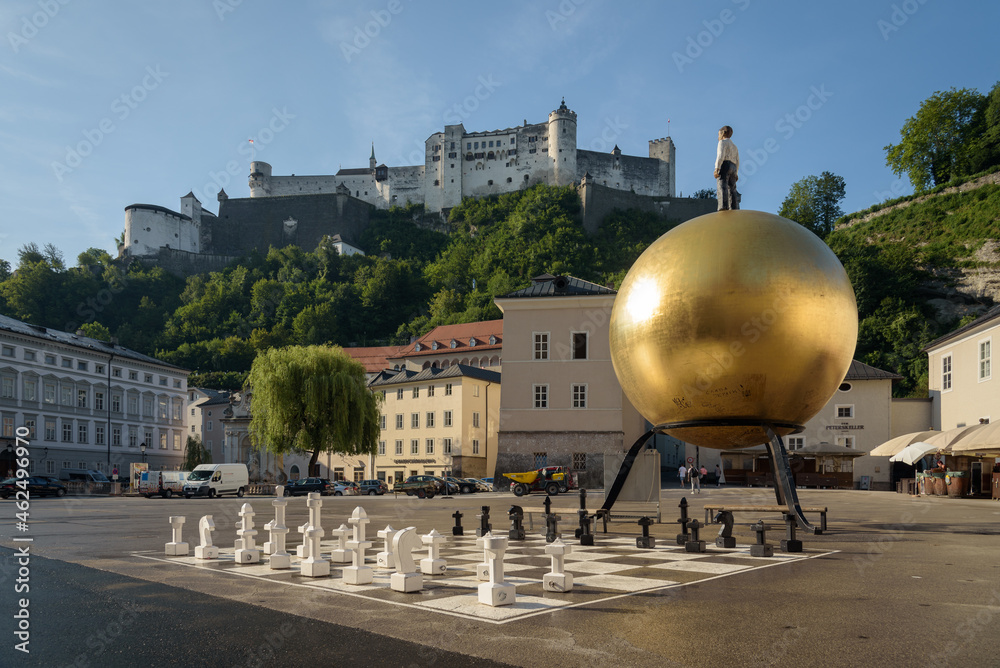 Fototapeta premium Golden Sphaera ball on Kapitelplatz in the old town of Salzburg with the Hohensalzburg castle on top of the mountain, Austria