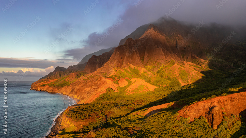 View of the Napali Coastline during sunset  at kalalau beach in Kauai, Hawaii. Peaks can be seen with several ridge lines and the ocean.