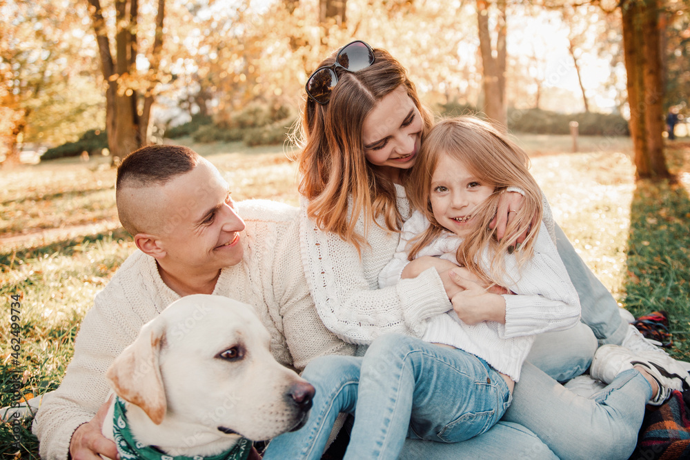 Happy beautiful family with dog labrador is having fun are sitting on green grass in park. Happy beautiful family with dog labrador is having fun are sitting on green grass in park.
