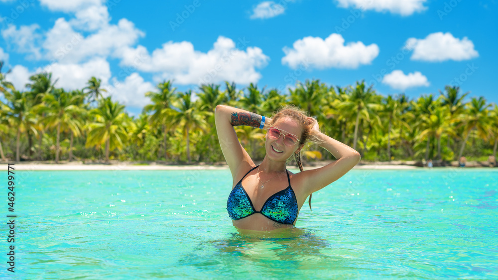 beautiful girl in a swimsuit on the beach of the island in sunny weather near the palm trees