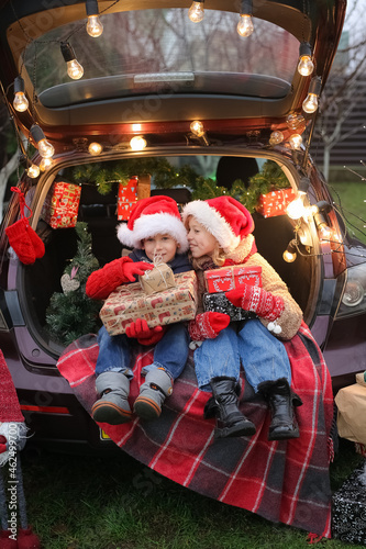 New Year's mood, brother and sister are sitting in a car full of gifts, children are having fun, rejoicing and choosing gifts