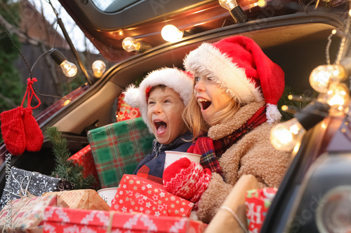 New Year's mood, brother and sister are sitting in a car full of gifts, children are having fun, rejoicing and choosing gifts