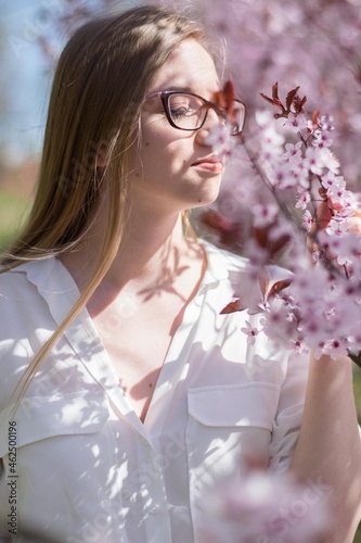 girl smelling pink flowers on a blossoming tree
