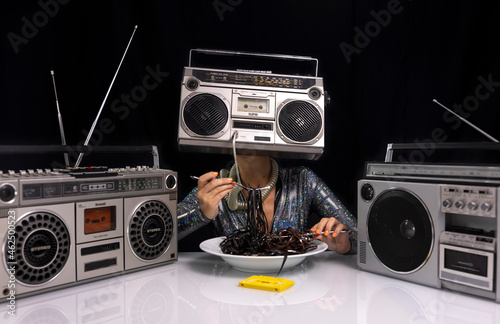 Woman with ghettoblaster as a head eating cassette tape