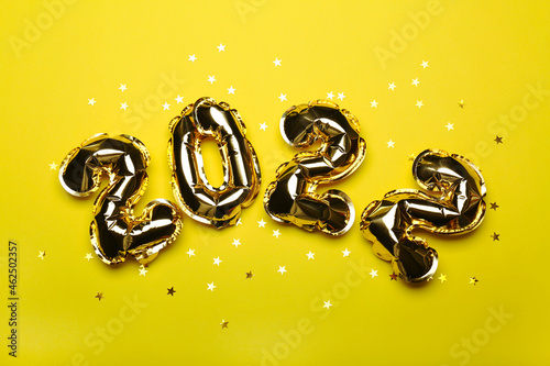 golden balloons numbers on a yellow background with sparkling golden confetti