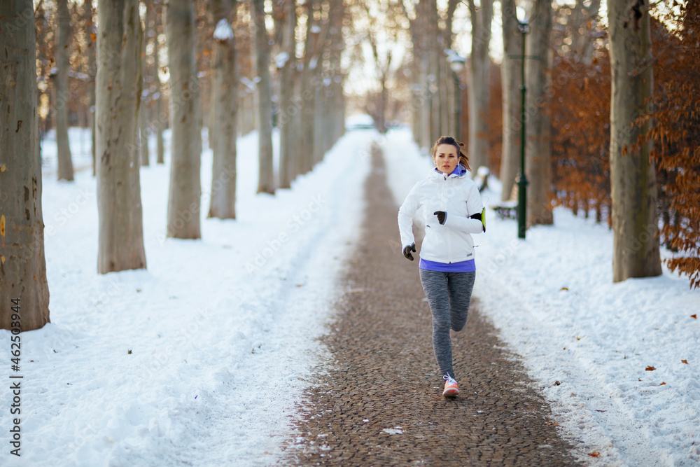 Full length portrait of young woman in white jacket jogging Full length portrait of young woman in white jacket jogging