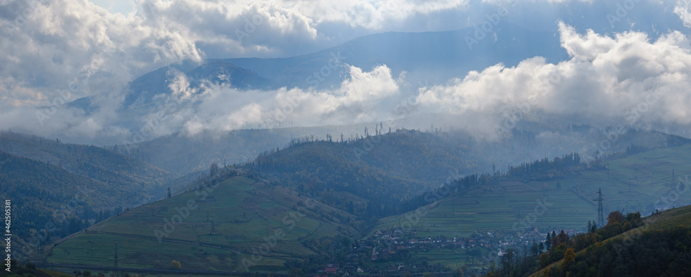 Morning foggy clouds in sunlight and autumn mountain countryside.  Ukraine, Carpathian Mountains, Borzhava Range, Transcarpathia.