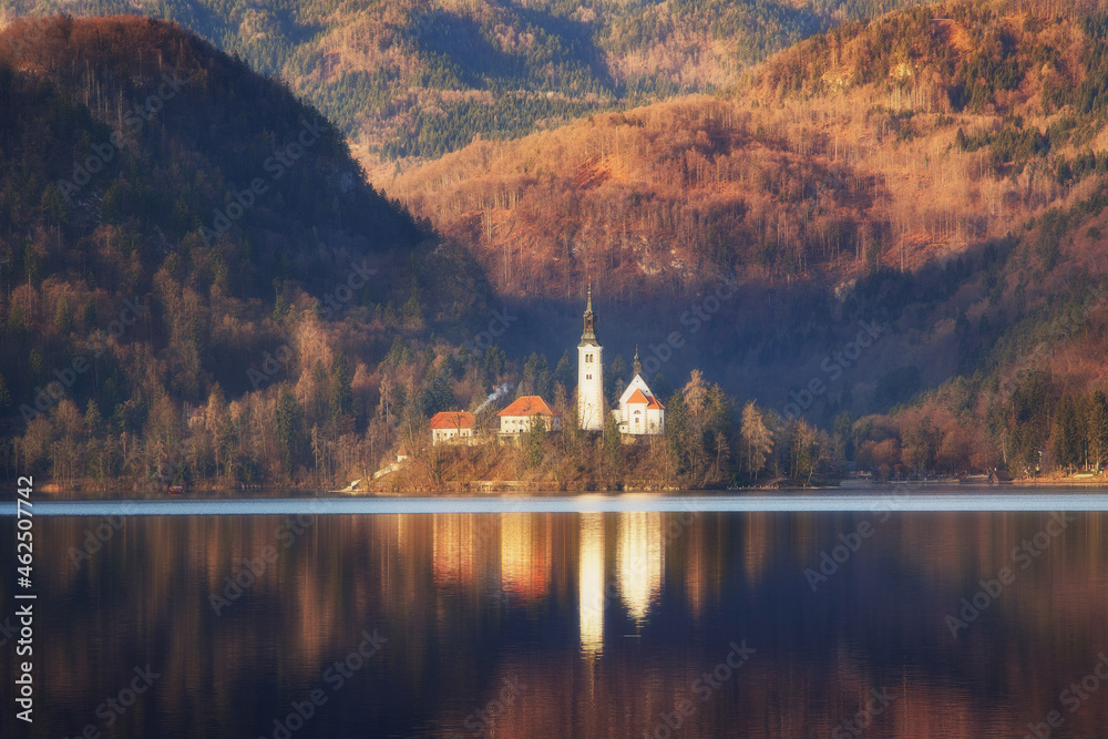 Morning landscape on Lake Bled, Slovenia. Island against the backdrop of mountain slopes, autumnal view, soft light, postcard. Desktop wallpaper, cell phone wallpaper.
