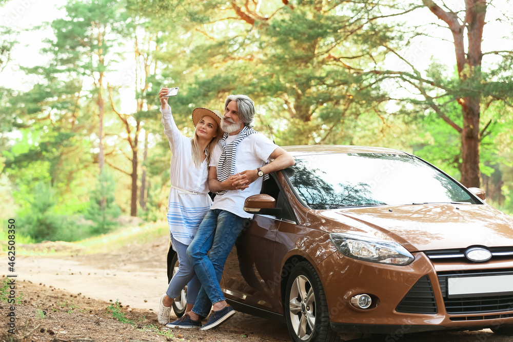 Happy mature couple taking selfie near car outdoors Happy mature couple taking selfie near car outdoors