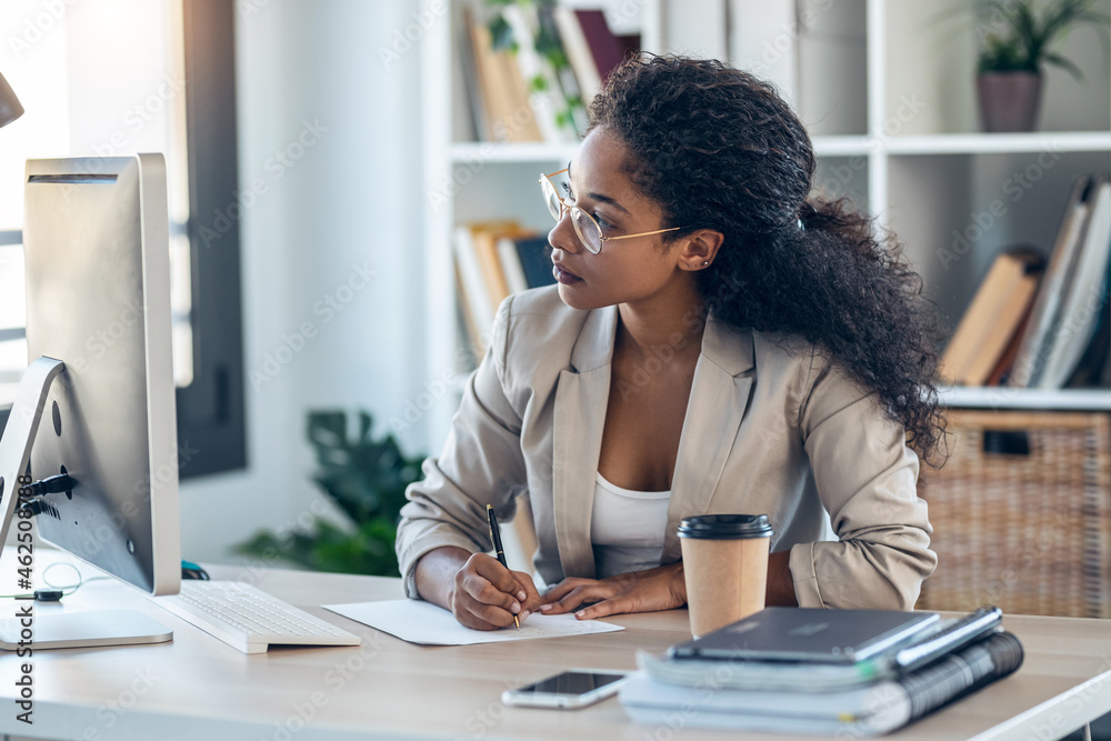 Elegant business woman working with laptop while checking and writing documents in the office. Elegant business woman working with laptop while checking and writing documents in the office.