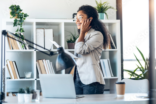 Elegant business woman talking with earphone while checking some documents in modern startup office.