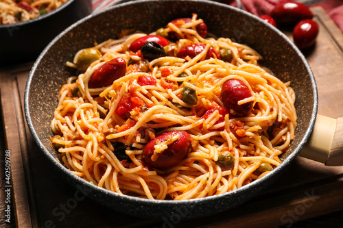 Frying pan of tasty Pasta Puttanesca on table