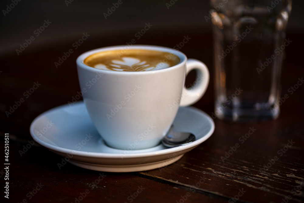 White cup of espresso coffee on wooden table. Space to copy your text.