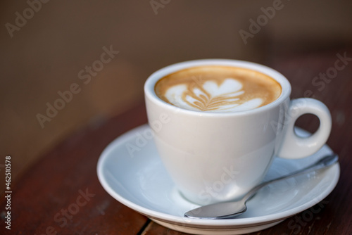 White cup of espresso coffee on wooden table. Space to copy your text.