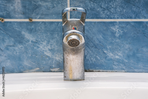 Dirty faucet with limescale, calcified water tap with lime scale on washbowl in bathroom photo