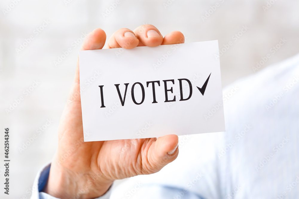Man holding paper with text I VOTED, closeup Man holding paper with text I VOTED, closeup