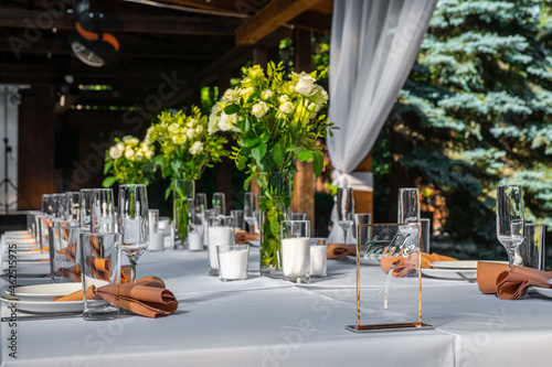 Wedding table setting decorated with fresh flowers. table number one. Wedding floristry. Banquet table for guests outdoors with a view of green nature at sunset. Bouquet with roses.
