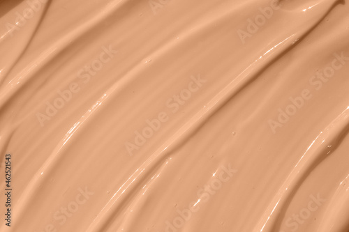 Make up base, cream textured background. Beige nude liquid foundation texture, concealer smear smudge drop. Closeup macro. Cosmetic tonal makeup moisturizer, bb cream swatch sample.