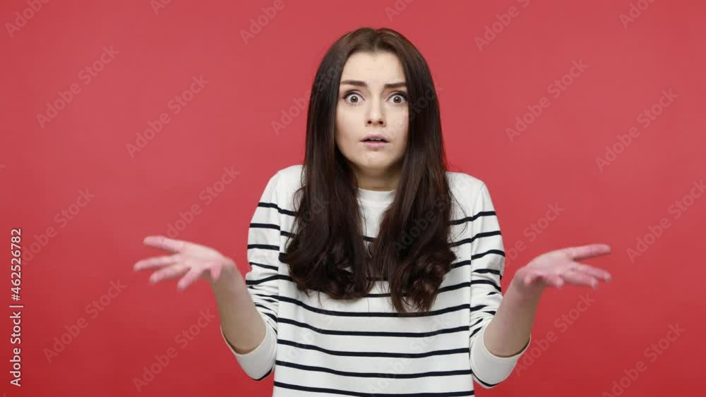 Portrait of young woman raising hands in anger and shouting why how, what do you want, quarreling, wearing casual style long sleeve shirt. Indoor studio shot isolated on red background. Portrait of young woman raising hands in anger and shouting why how, what do you want, quarreling, wearing casual style long sleeve shirt. Indoor studio shot isolated on red background.