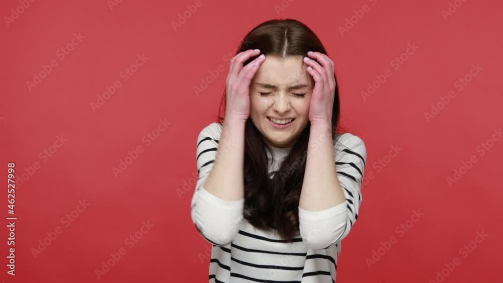 Portrait of nervous brunette woman imitating gun, looking at camera with panic stressed expression, wearing casual style long sleeve shirt. Indoor studio shot isolated on red background. Portrait of nervous brunette woman imitating gun, looking at camera with panic stressed expression, wearing casual style long sleeve shirt. Indoor studio shot isolated on red background.