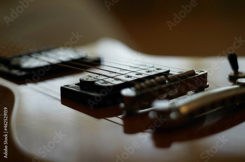 Streams and Bridges. Closeup shot of a lacquered wooden body of electric guitar with bridge, strings and pickups photo