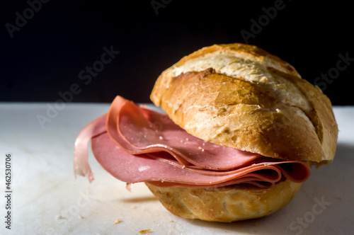 traditional bologna bread on a white board with black background, copy space and selective focus.